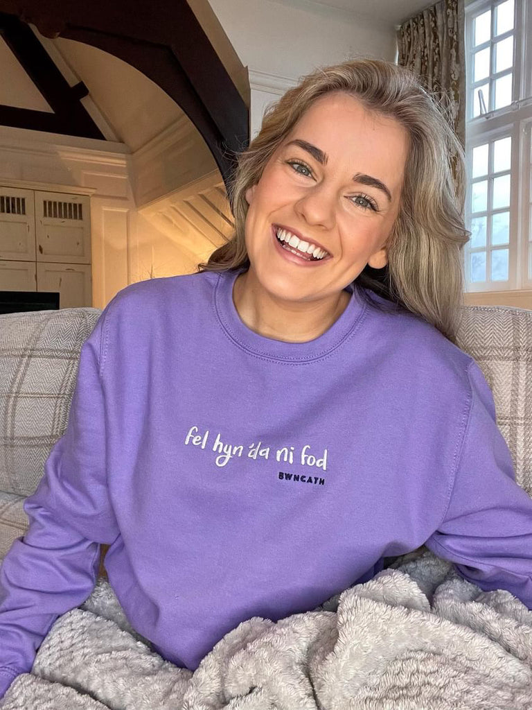 Heledd wearing a lavender sweatshirt with the song lyrics Fel Hyn 'Da Ni Fod by Bwncath