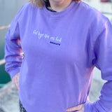 Close up of a lilac colour sweatshirt with the song lyrics Fel Hyn 'Da Ni Fod by Bwncath embroidered on the front