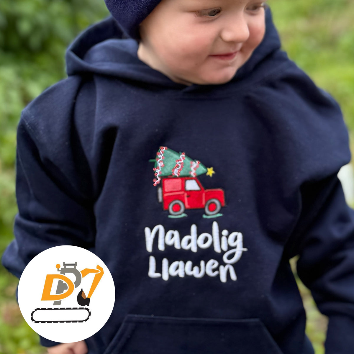 A child wearing a Welsh Christmas jumper in navy featuring a red Land Rover design and the words Nadolig Llawen